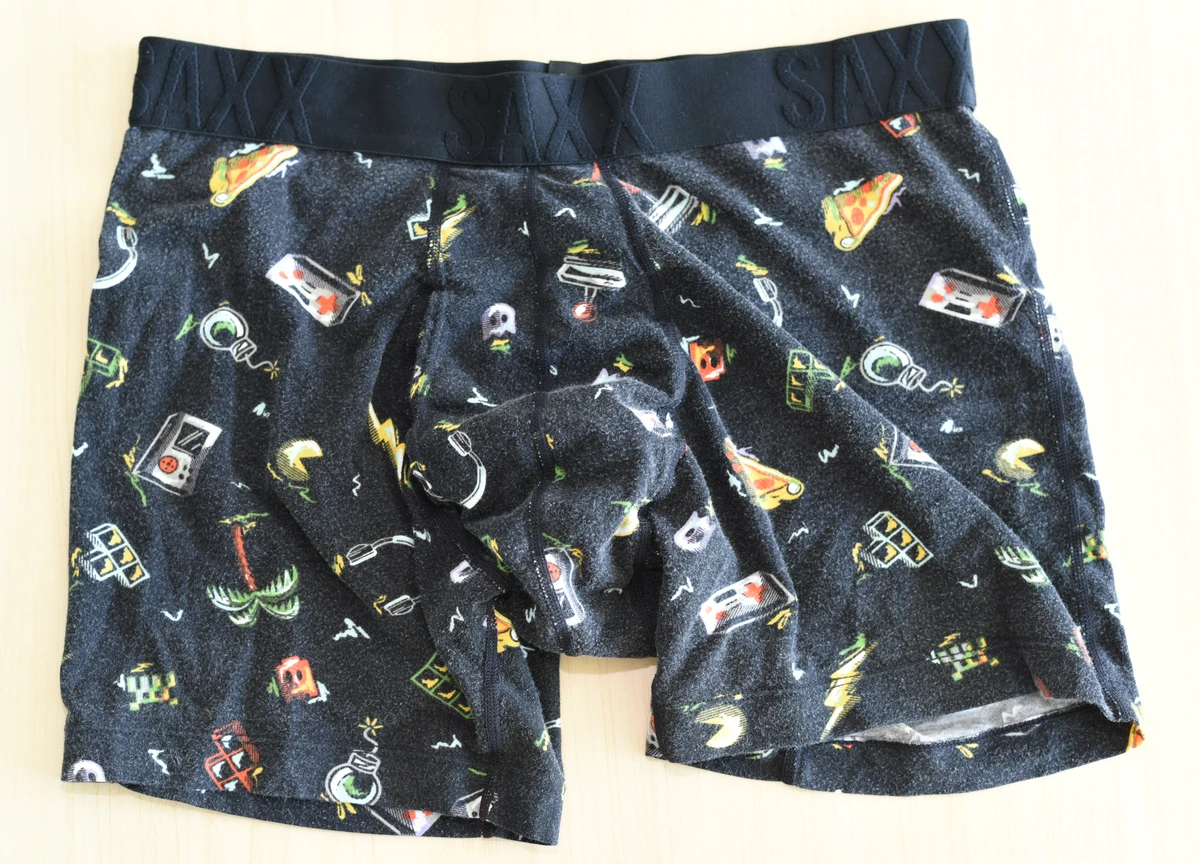Front flat lay of the black SAXX boxer brief with colorful illustrated motifs, a black waistband and visible fabric fuzz.